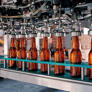 Las botellas de vidrio recorren una planta de fabricación de bebidas. La monitorización de la dureza del agua es importante para gestionar la calidad del producto.