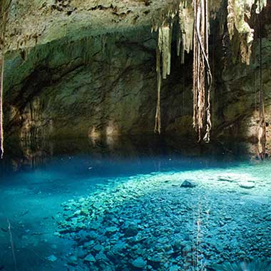 Un lago de agua turquesa brilla en una cueva. El color se debe a los minerales finamente molidos que están suspendidos en el agua.